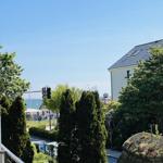 Blick auf den Strand mit Bäumen und einem Haus im Hintergrund.
