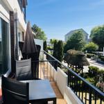 Terrasse mit Tisch, Stühlen und Sonnenschirm. Blick auf Garten und Straße.