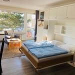 Schlafzimmer mit Bett, Schrank und Balkonblick