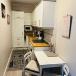 Küche mit Arbeitsplatte, Spüle und Essplatz mit Stühlen.