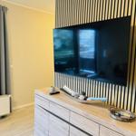 TV an Wand montiert, Holzkommode mit Dekoration und graue Vorhänge