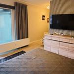 Schlafzimmer mit Bett, TV und Balkonzugang.