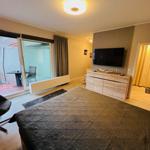 Schlafzimmer mit Bett, TV und Balkonzugang.