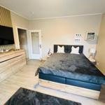 Schlafzimmer mit Bett, TV und Holzmöbeln