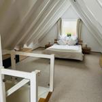 Schlafzimmer mit Dachschrägen, Bett, Nachttische und Fenster.