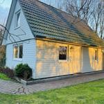 Haus mit hellen Wänden, schwarzem Dach und Vorgarten