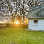 Haus mit grünem Rasen und Bäumen im Hintergrund bei Sonnenuntergang.
