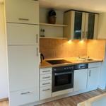 Küche mit Schränken, Herd, Spüle und Holzboden.