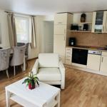 Wohnküche mit Essbereich, weiße Sitzgelegenheiten und Holzboden.