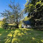 Haus mit Garten, umgeben von Bäumen unter blauem Himmel