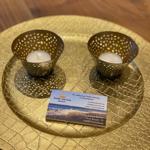 Goldener Teller mit zwei Kerzenhaltern und Visitenkarte.