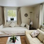 Wohnzimmer mit Sofa, Schlafcouch und Fenstern mit Blick auf Garten.