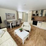 Wohnung mit Küche, Essbereich und Wohnzimmer mit Holzboden und weißen Möbeln.