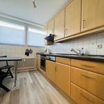 Küche mit Holzschränken, Arbeitsplatte und Fenster