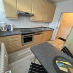 Küche mit Holzschränken, Edelstahlgeräten und Essbereich.