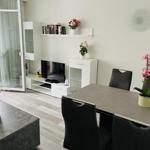 Wohn- und Essbereich mit TV, Tisch, Stühlen und Pflanzen. Terrasse über Glastür zugänglich.