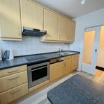 Küche mit Holzschränken, Edelstahlherd und Arbeitsplatte.