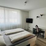 Schlafzimmer mit Doppelbett, Schreibtisch und TV an der Wand.