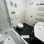 Badezimmer mit Badewanne, Dusche, Waschbecken und Toilette.