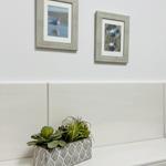 Wand mit zwei Bildern und Pflanze auf Waschtisch