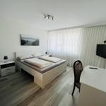 Schlafzimmer mit Bett, Schreibtisch und Fernseher an der Wand.