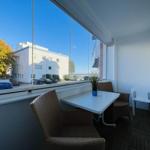 Terrasse mit Tisch, Stühlen und Blick auf Gebäude und Parkplatz.