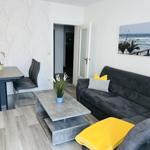 Wohnzimmer mit Sofa, Esstisch und Wandbild an der Wand.