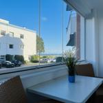 Terrasse mit Tisch und Stühlen, Blick auf Parkplatz und Gebäude.