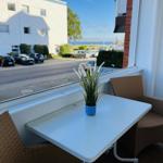 Balkon mit Tisch und zwei Stühlen, Blick auf Straße und Wasser.
