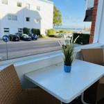 Terrasse mit Tisch und Stühlen. Blick auf Straße und Gebäude.