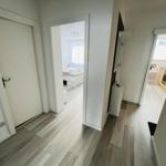 Flur mit Blick in Schlafzimmer und Küche. Holzboden und weiße Wände.