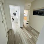 Flur mit Holzboden führt in Küche und Arbeitszimmer.