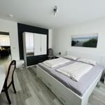 Schlafzimmer mit Doppelbett, Kleiderschrank und Tisch. Blick in Wohnbereich.