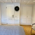 Schlafzimmer mit Bett, Stuhl und weißen Türen an den Wänden.