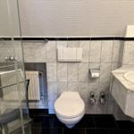 Badezimmer mit Dusche, Toilette und Waschbecken aus Marmor