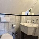 Badezimmer mit Marmorfliesen, Waschbecken und Toilette