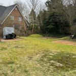 Haus mit Garten, Grillplatz und Bäumen im Hintergrund.