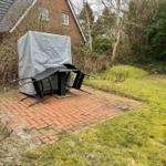 Garten mit Terrasse, gedeckter Sitzbereich und Grünflächen.