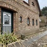 Haus mit Backsteinfassade, grüner Tür und Kiesweg. 