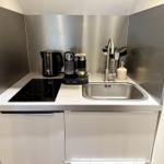 Küchenbereich mit Spüle, Induktionskochfeld und Kaffeemaschine.