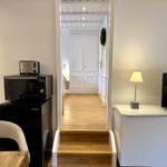 Küche mit Kühlschrank und Mikrowelle. Treppenhaus führt zu Schlafzimmer.