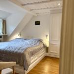 Schlafzimmer mit Dachschrägen, Bett, Fenster und Holzboden.