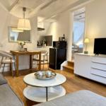 Wohnbereich mit Essplatz, Küchenzeile und TV-Schrank. Holzboden und weiße Wände.