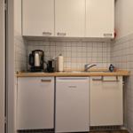 Küche mit weißen Schränken, Spüle und Kühlschrank.