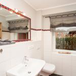 Badezimmer mit Waschbecken, Toilette und Fenster mit Blick nach draußen.