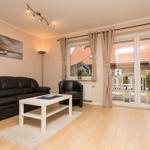 Wohnzimmer mit Sofa, Couchtisch und Terrasse. Blick auf Garten und Nachbarhaus.