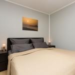 Schlafzimmer mit Bett, Nachttischen und Wandbild.