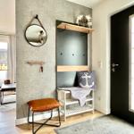 Eingangsbereich mit Wandgarderobe, Spiegel und Sitzgelegenheit.