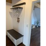 Eingangsbereich mit Kleiderständer und Sitzbank. Durchgang in Wohnraum mit Pflanze.