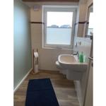 Badezimmer mit Waschbecken, Toilette und Fenster mit Jalousie.